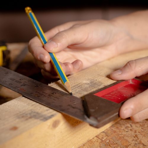 Female hands using a try square to check that the woodworking corners are square with a set collection of working hand tools for the wooden, Toolset with the do it yourself (DIY)in wood studio