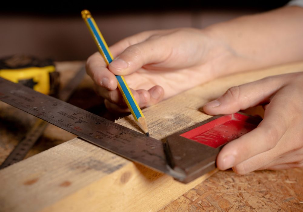 Female hands using a try square to check that the woodworking corners are square with a set collection of working hand tools for the wooden, Toolset with the do it yourself (DIY)in wood studio